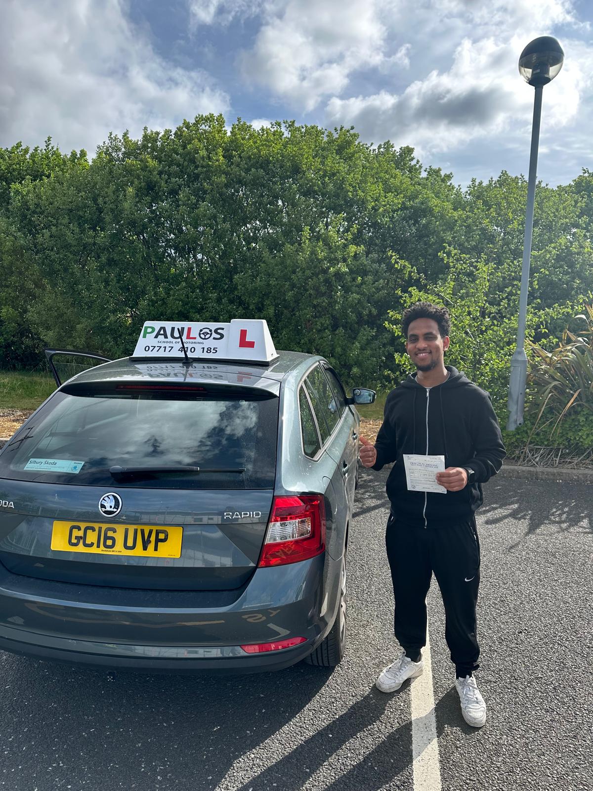 Smiling pupil giving a thumbs up with his driving test pass certificate