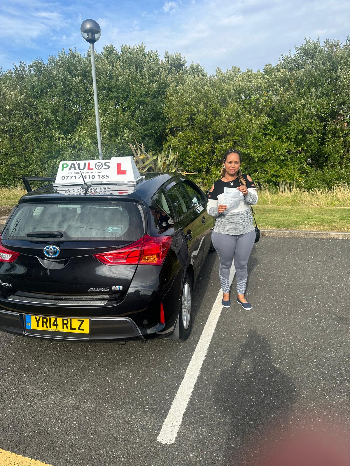 Pupil proudly showing her driving test pass certificate next to a Paulos tuition car